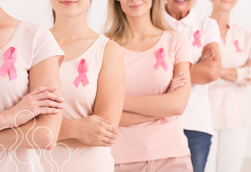 A few women wearing pink breast cancer awareness ribbons standing together